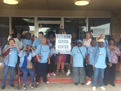Senior residents smiling, holding a sign that says Hutchins Senior Center