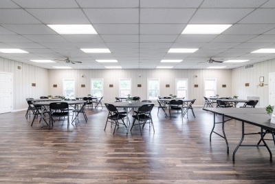 Photo of main room in the community center, containing round tables and chairs