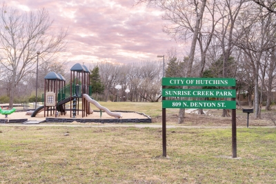 Green sign for Sunrise Creek park in front of a playground