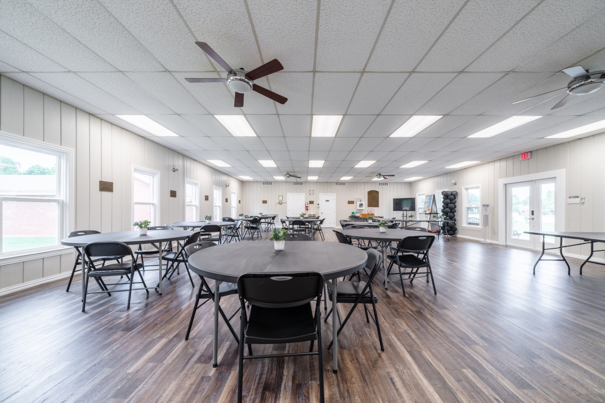 Photo of the dining area of the community center, showing round tables with chairs